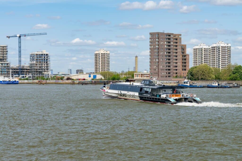 Uber Boat on Thames River with modern residential buildings in the background